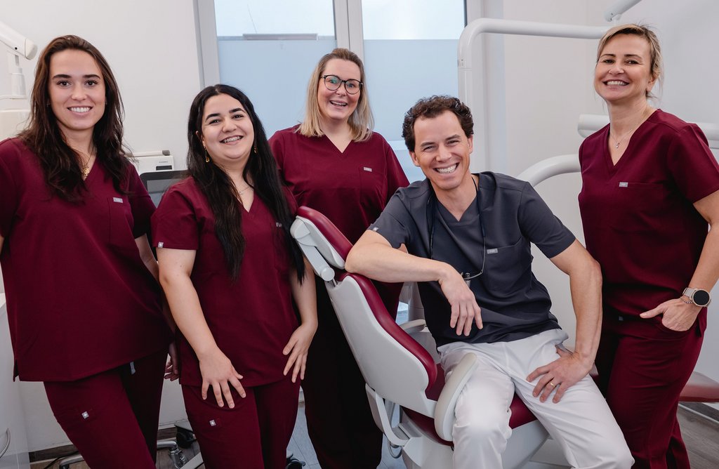 Dr. Sigmund und zahnmedizinische Fachangestellte in Arbeitskleidung im Behandlungszimmer, bereit, Patienten zu betreuen.