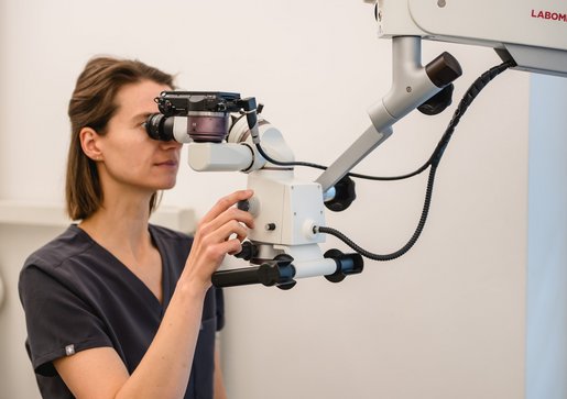 Wurzelkanalbehandlung mit Mikroskop Maja Schreiner nutzt ein Mikroskop mit Sehaufsatz in einem hellen Raum zur Wurzelkanalbehandlung mit Mikroskop.